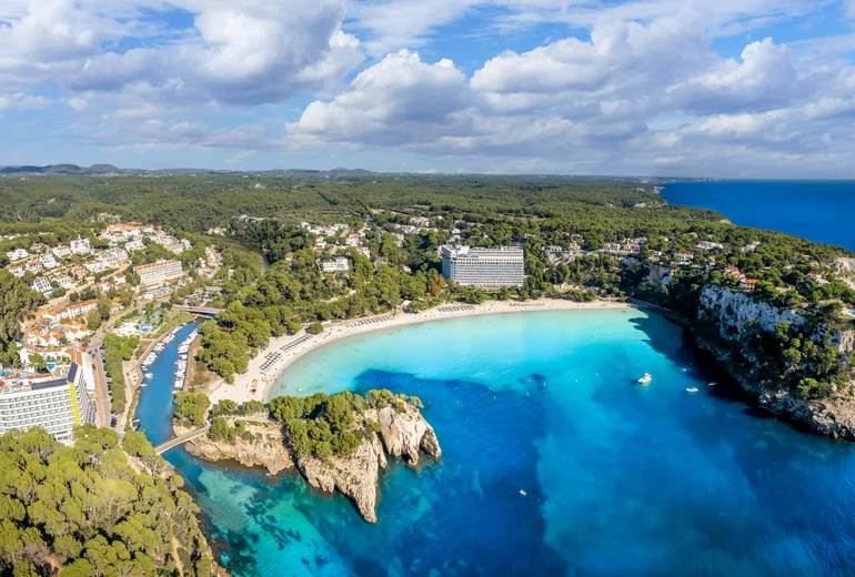 Aerial of Cala Galdana beach and turquoise bay with hotels on Menorca