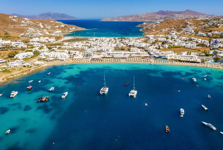 Aerial of Ornos bay on Mykonos with anchored catamarans and beach clubs
