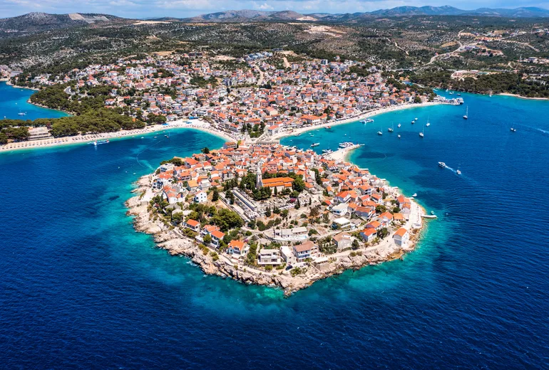 Aerial of Primosten old-town islet, beaches and surrounding turquoise water, Croatia