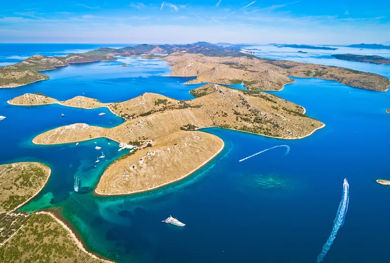 Aerial of the Kornati archipelago with a sheltered anchorage bay and white boat wakes