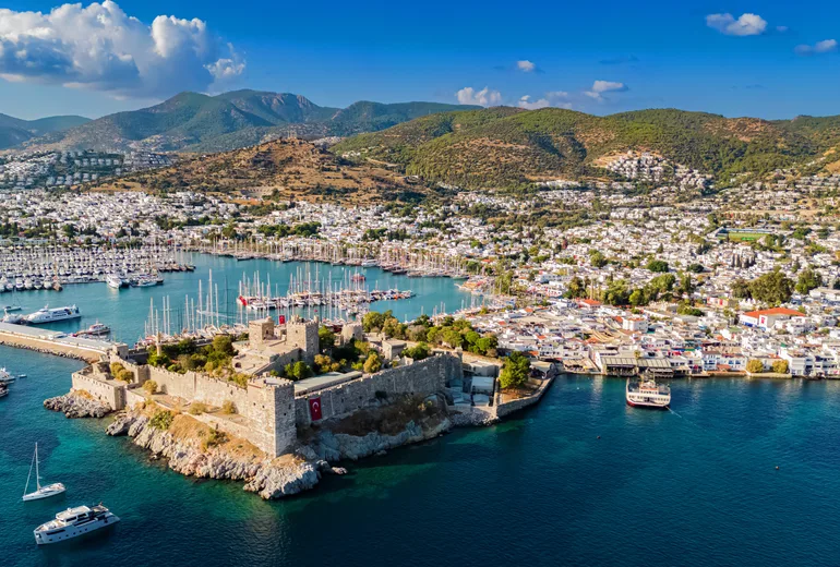 Aerial panorama of Bodrum castle, marina masts, whitewashed town and hills, Türkiye