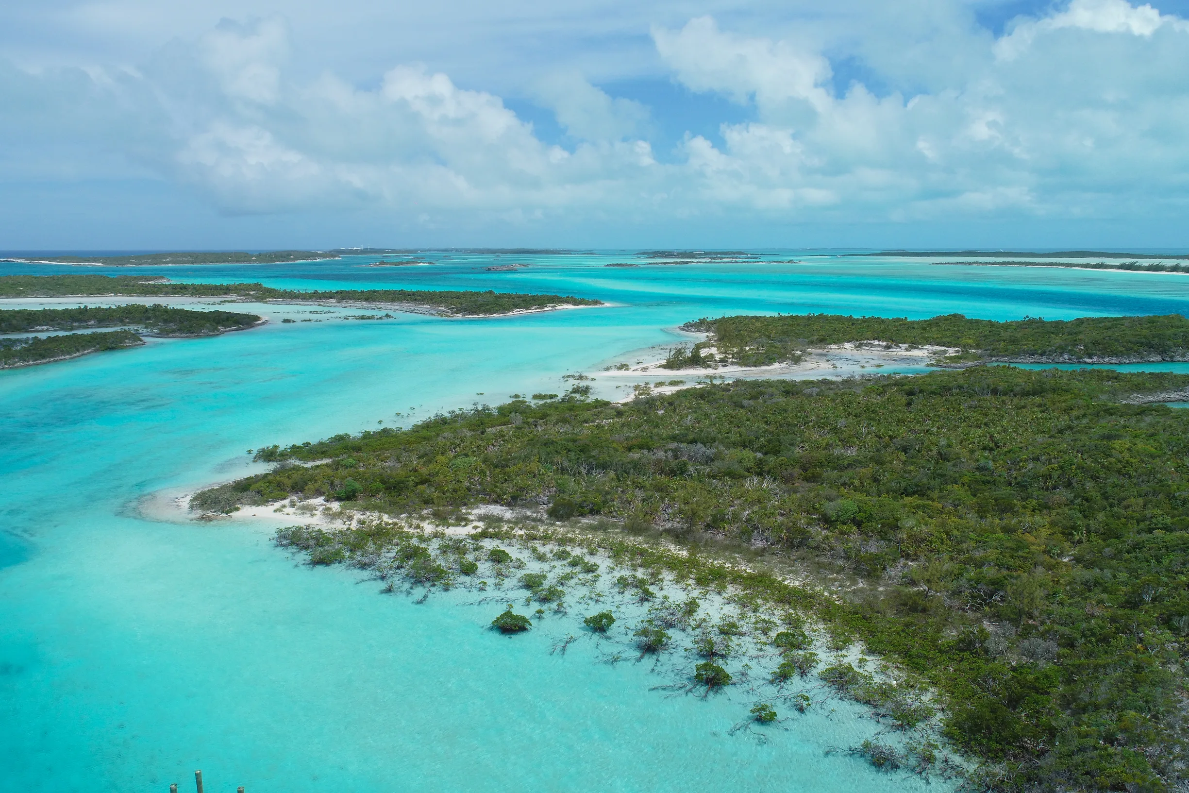 Aerial of low green cays and winding turquoise sand channels