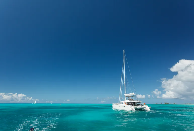 Lagoon-style sailing catamaran with guests cruising turquoise shallow banks in the Caribbean