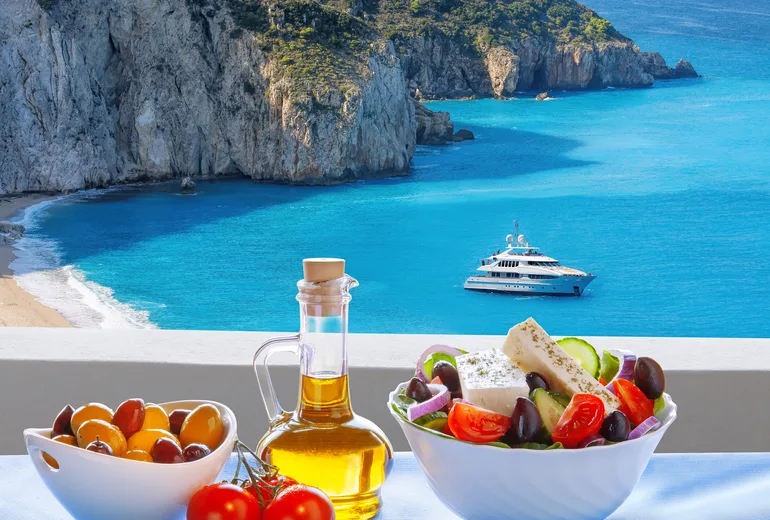 Mediterranean lunch spread overlooking a quiet cliff-backed anchorage