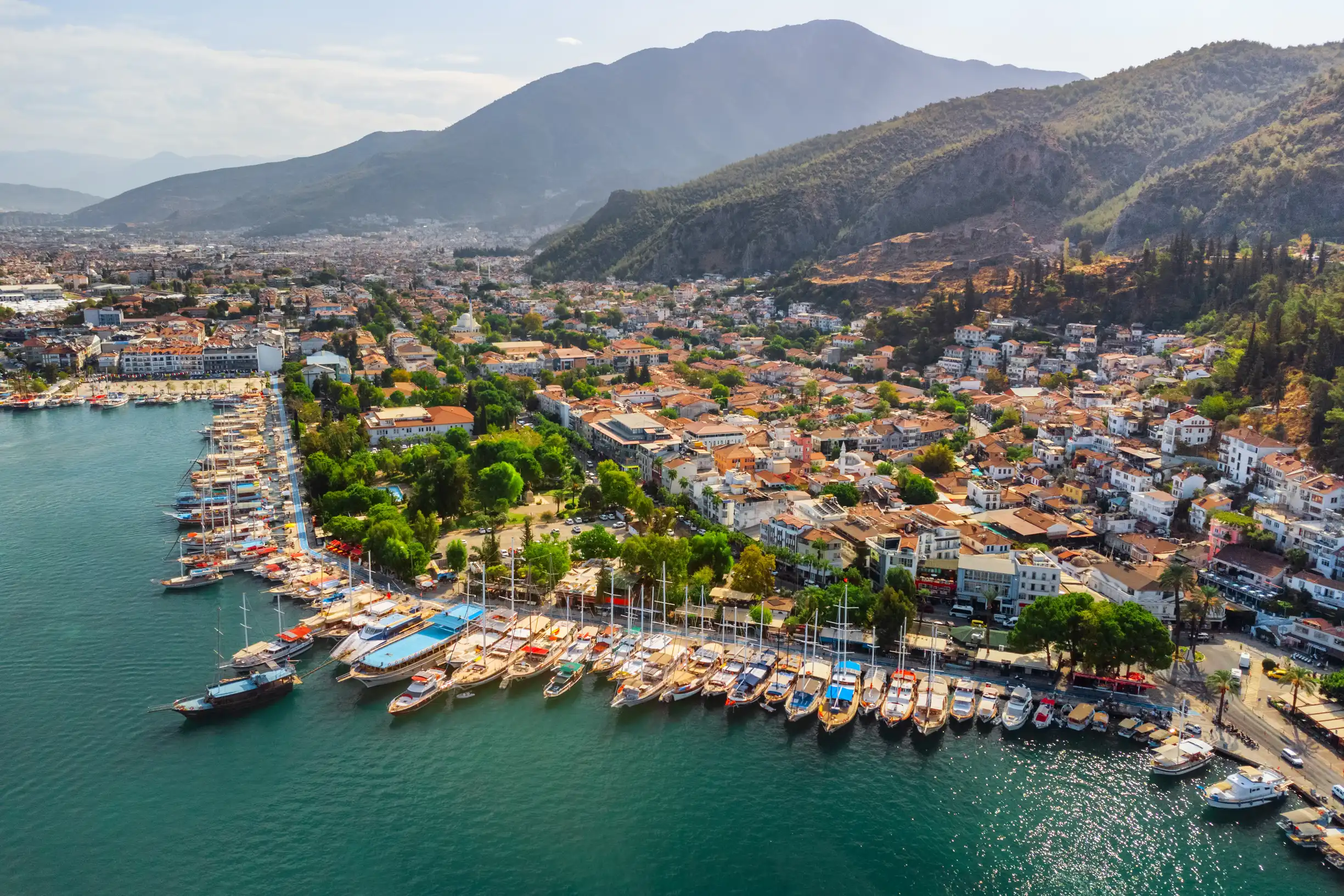 Aerial of Fethiye waterfront with gulets lined along quay beneath mountains