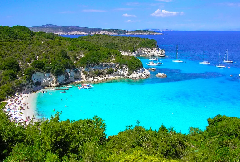 Sailboats anchored off a white beach in turquoise Voutoumi bay, Antipaxos, Greece