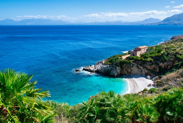 Secluded white pebble cove with palms in the Zingaro Nature Reserve, western Sicily