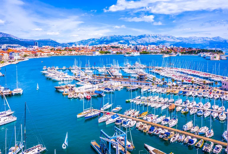 Split city marina packed with sailboats with mountains rising behind, Croatia