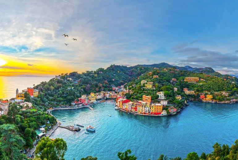 Sunset over a Riviera harbour village with yachts moored in the bay