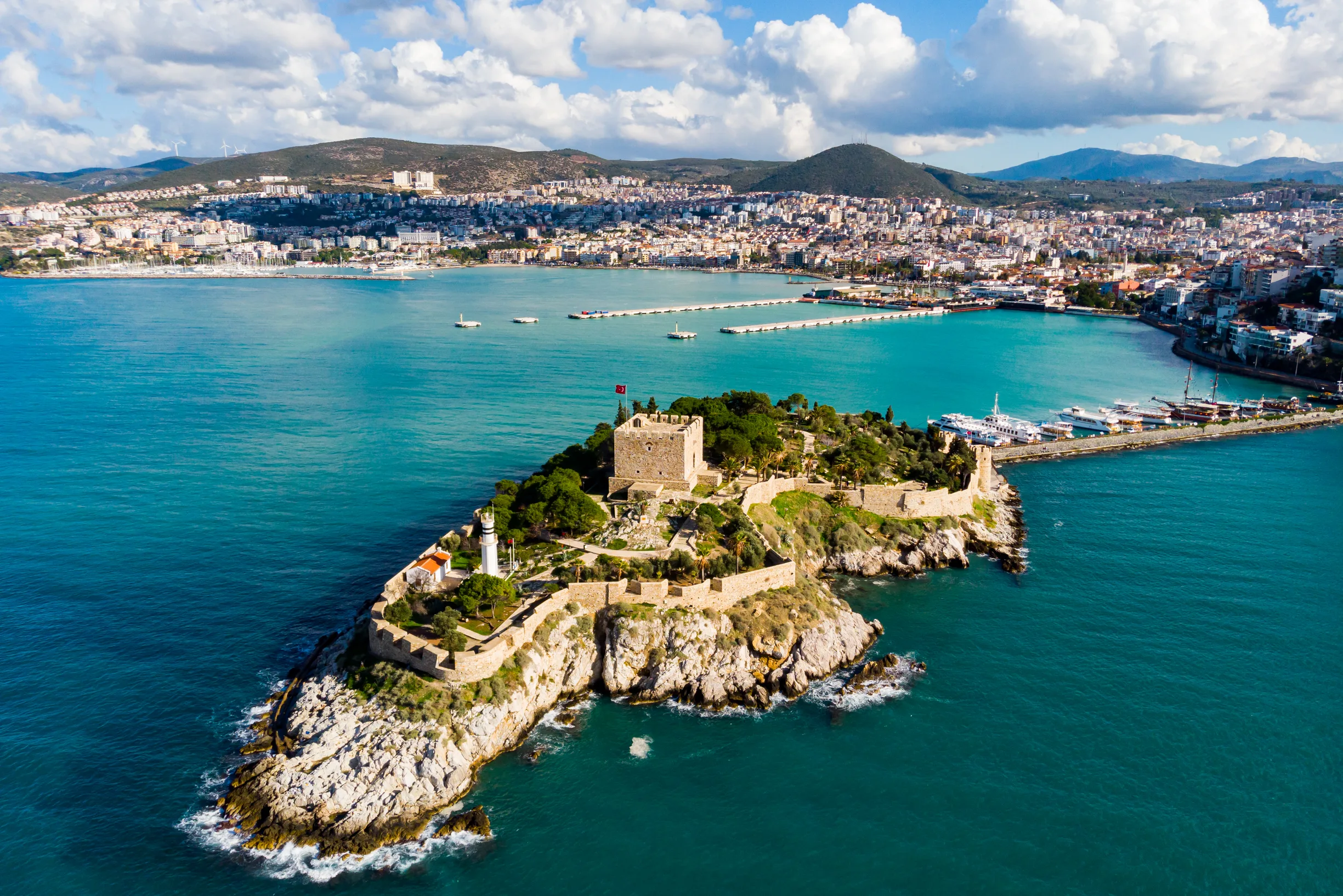Aerial of Kusadasi Pigeon Island fortress and lighthouse with city waterfront behind